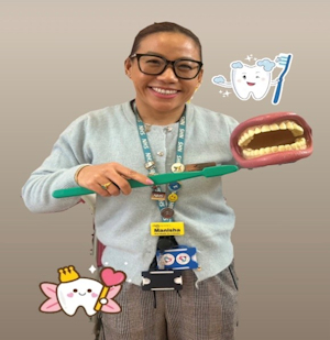 Smiling woman holding large toothbrush